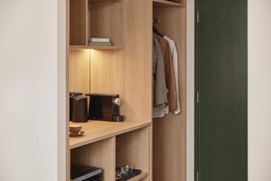 Un armario de madera con estantes, una barra para colgar ropa y una cafetera.