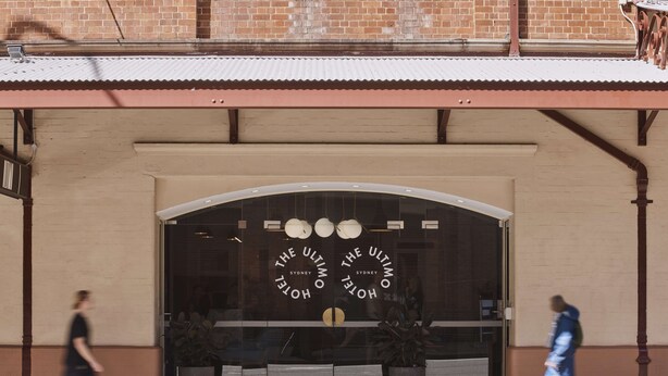 Entrada de un hotel con un amplio ventanal en arco y un letrero que dice "The Ultimo Hotel Sydney".