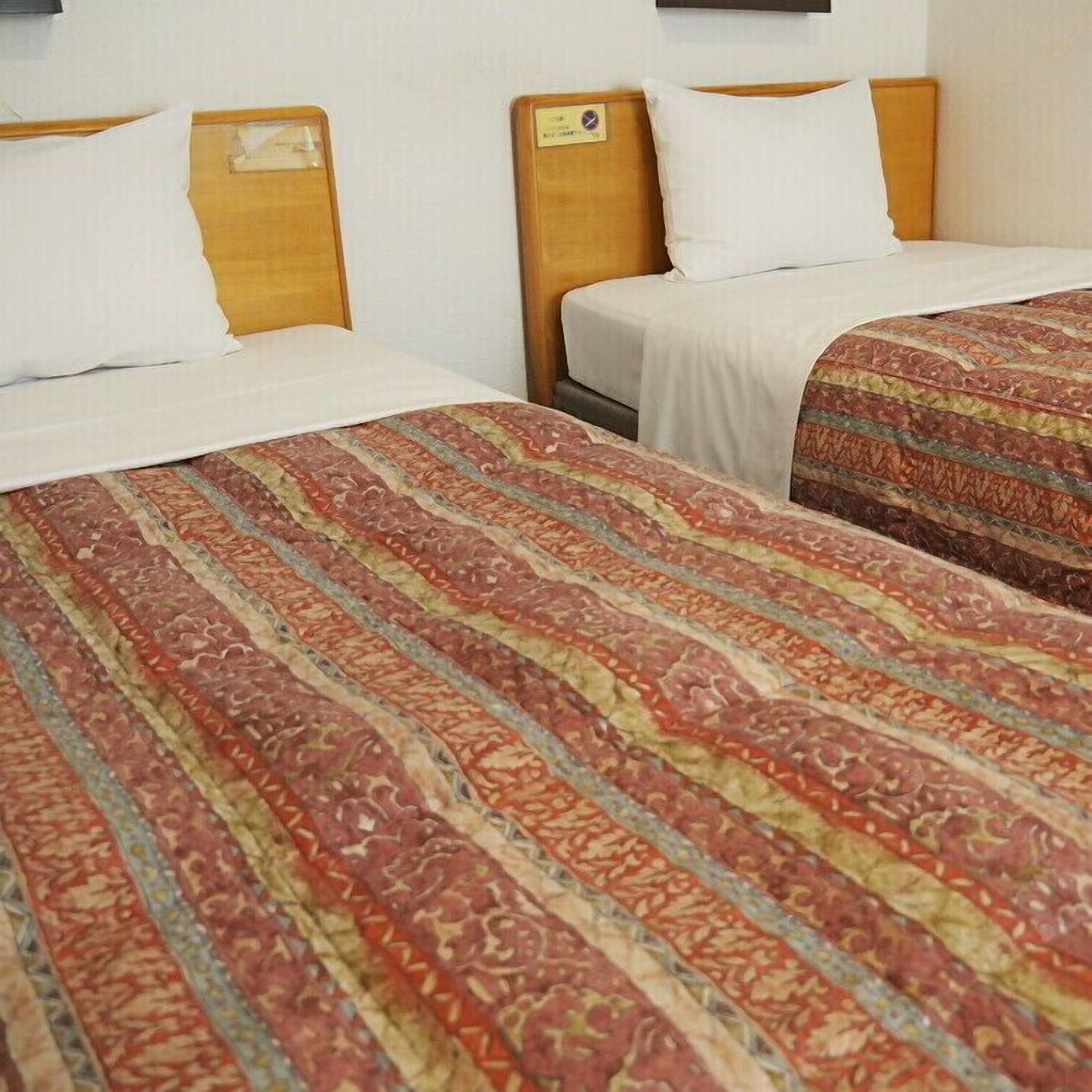 Dos camas individuales con cabeceros de madera y ropa de cama blanca.