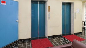 A hotel lobby with two elevators, a blue door, and red carpets. - Tabist Hotel Tetora Ikebukuro (Tokyo)