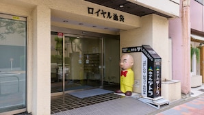 A hotel entrance with a glass door, a yellow mascot, and a signboard with the hotel's name and contact number. - Tabist Hotel Tetora Ikebukuro (Tokyo)