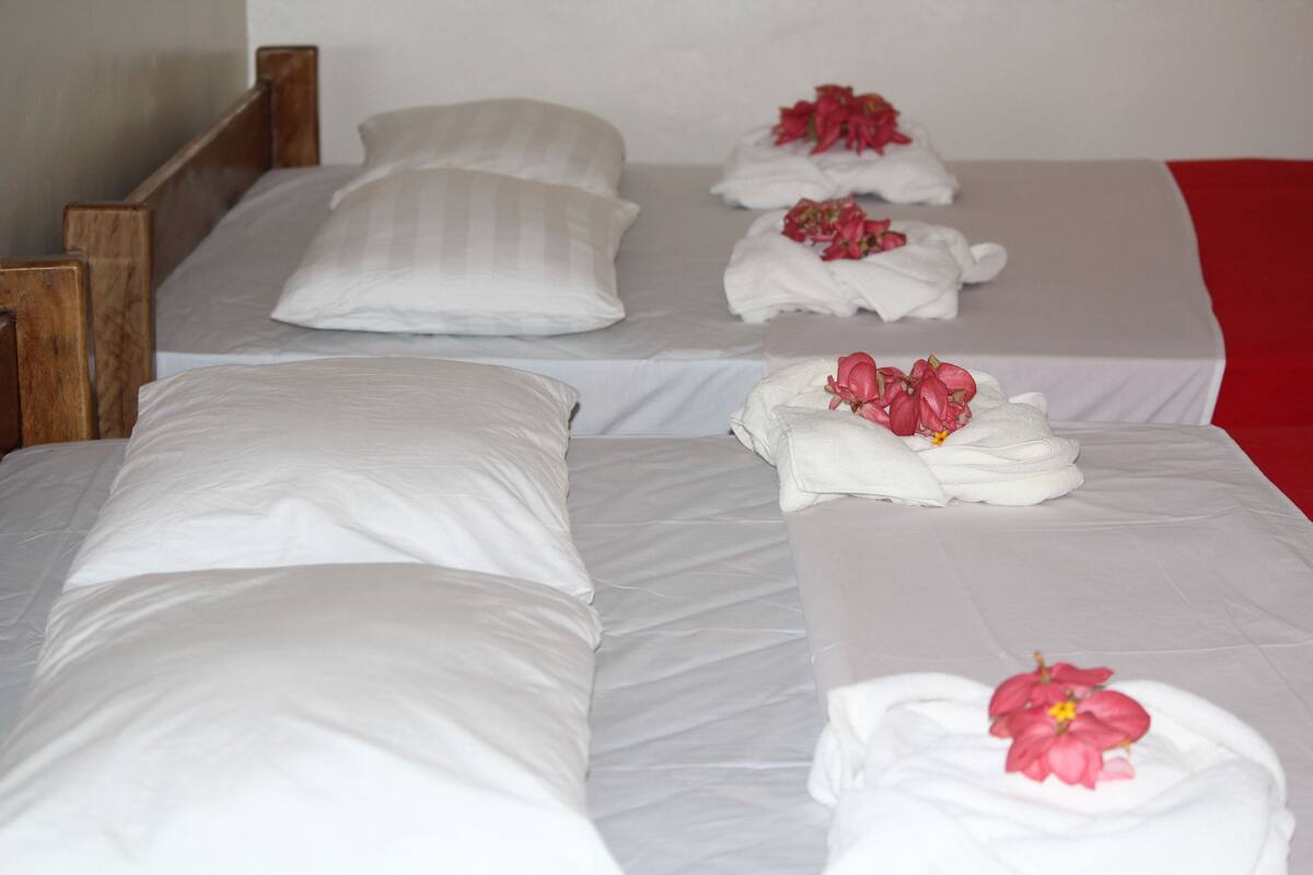 A hotel room with three beds, each with white linens and pillows.