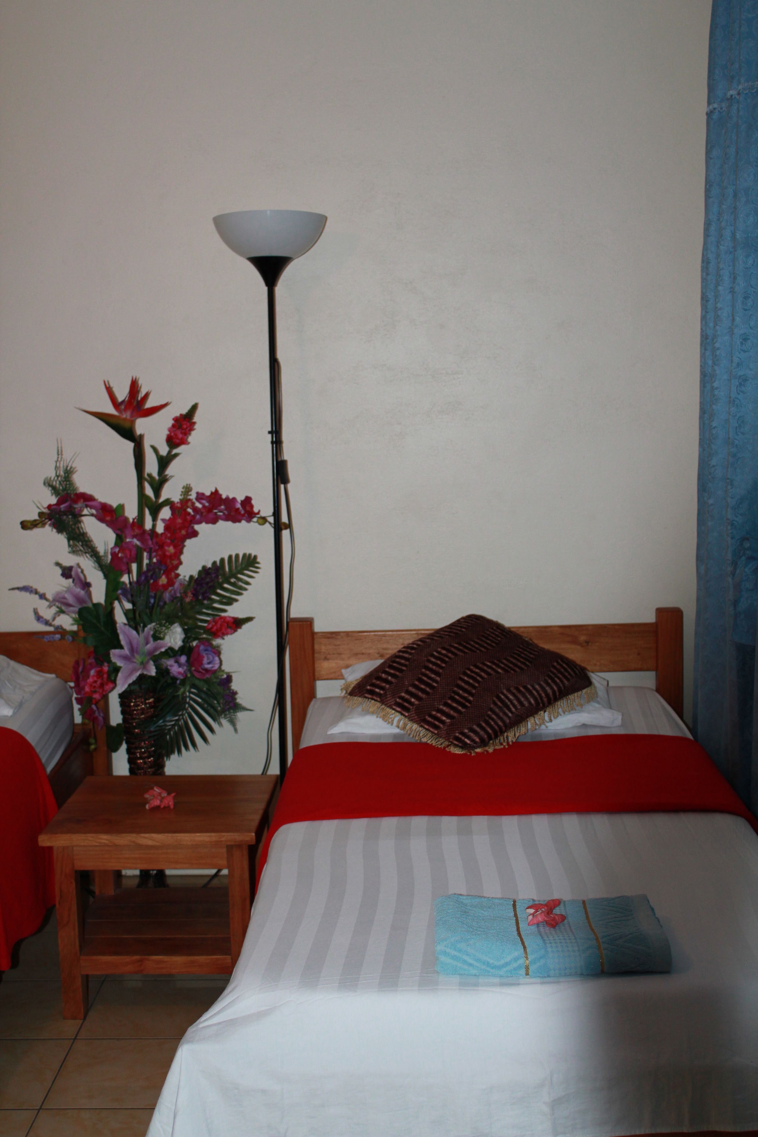 A hotel room with a bed, a nightstand, a lamp, and a floral arrangement.