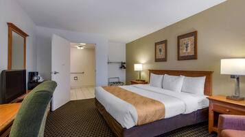 A hotel room with a bed, a desk, a chair, a television, and a bathroom door.