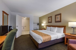 A hotel room with a bed, a desk, a chair, a television, and a bathroom door. - Quality Inn Palm Springs Downtown (Palm Springs)