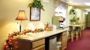 A hotel kitchen with a lamp, Christmas decorations, a coffee machine, and a trash can. - Badger Motel (Chippewa Falls)