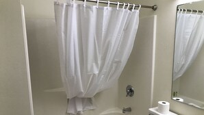 A bathroom with a bathtub, toilet, and a shower curtain. - Badger Motel (Chippewa Falls)