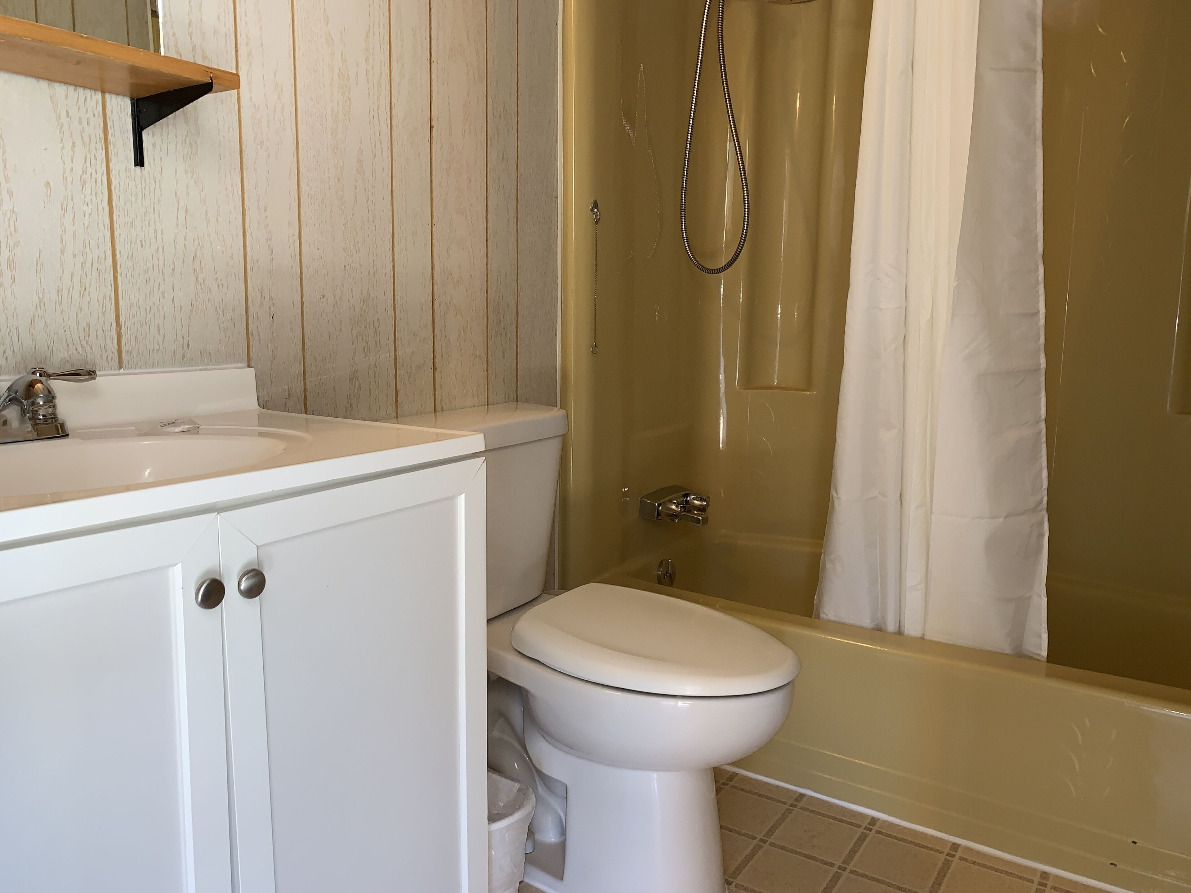 Un baño con lavamanos, inodoro y zona de ducha blanca.