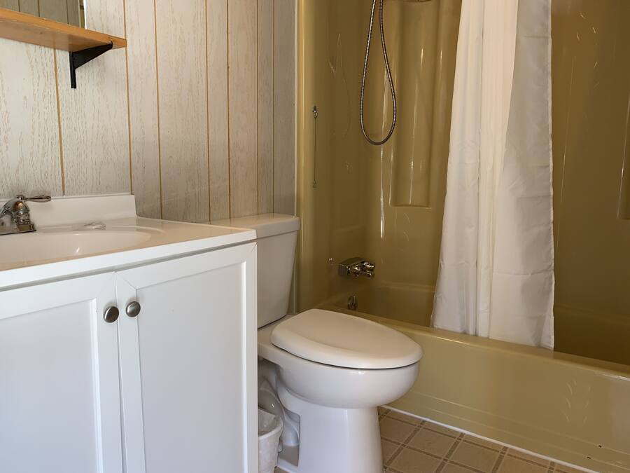 Un baño con lavamanos, inodoro y zona de ducha blanca.