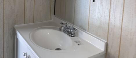 A bathroom with a white sink, a mirror, and a shelf above the sink.