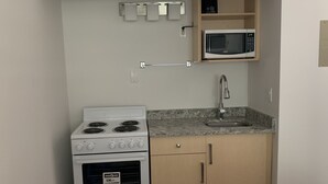 A compact kitchen with a stove, oven, microwave, and a sink. - Greenview Motel and RV Park (Greenwood)