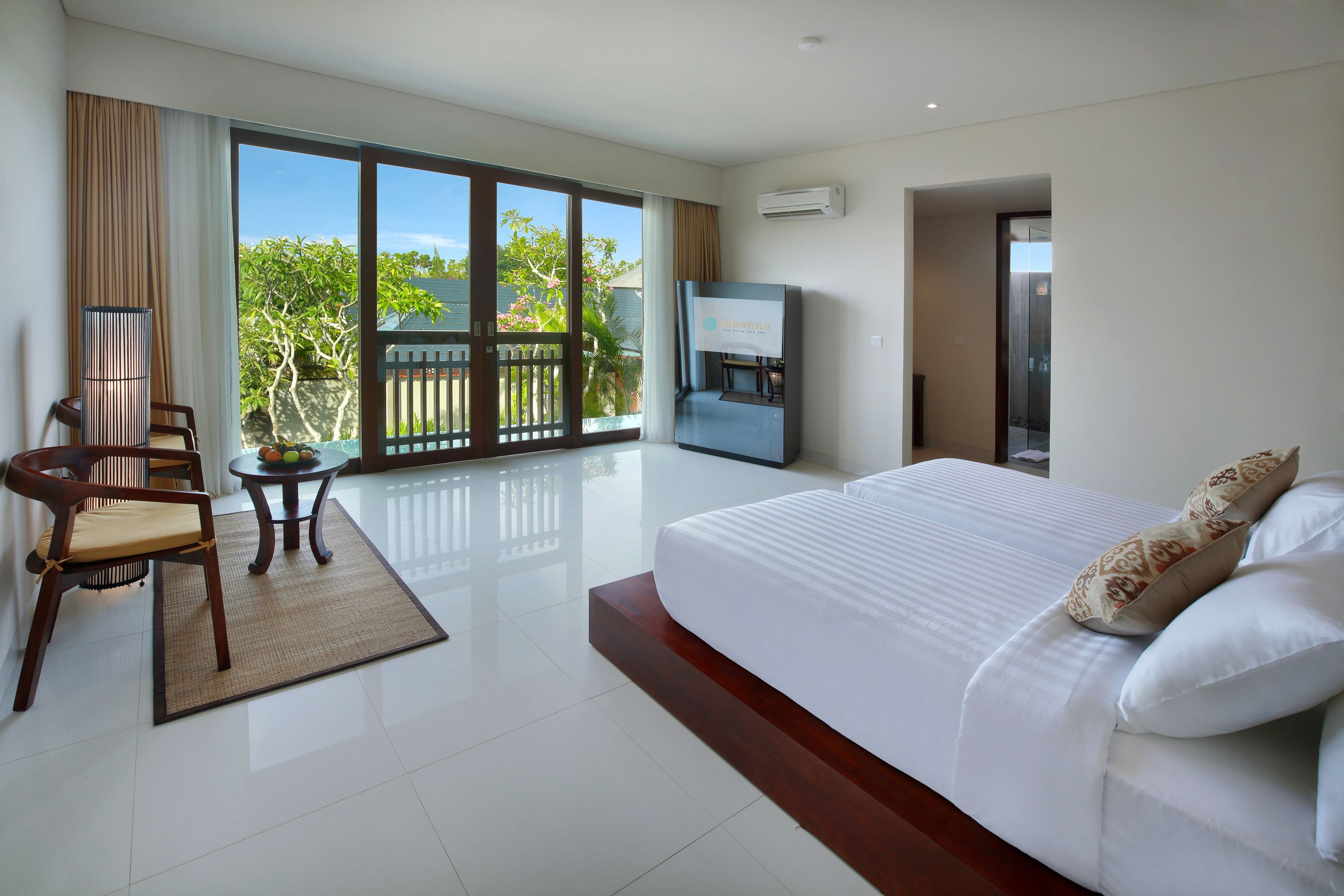 A modern hotel room with a large bed, a TV, a desk, and a view of the outdoors.
