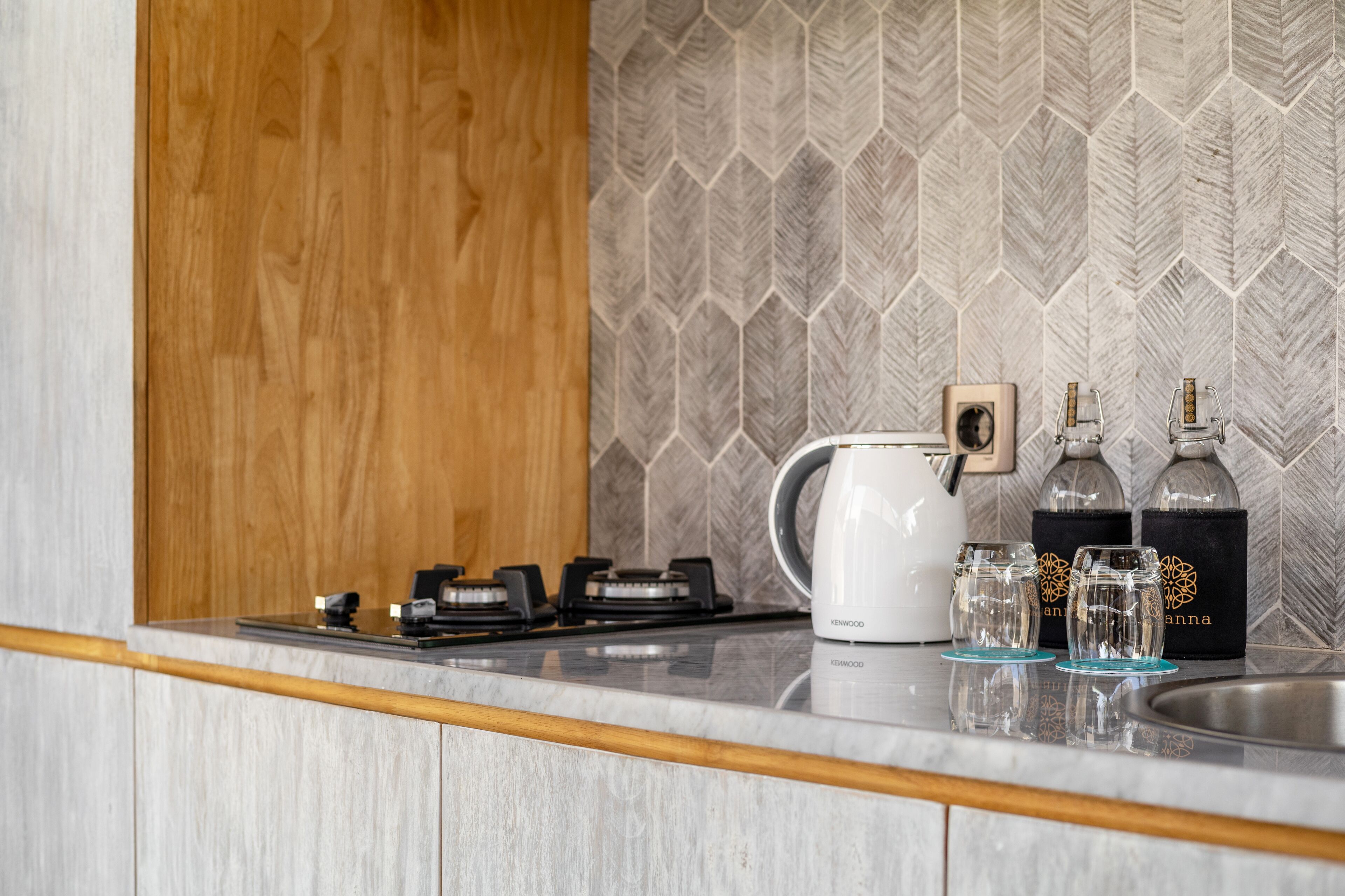 A kitchen with a gas stove, a kettle, and two glass decanters on the counter.