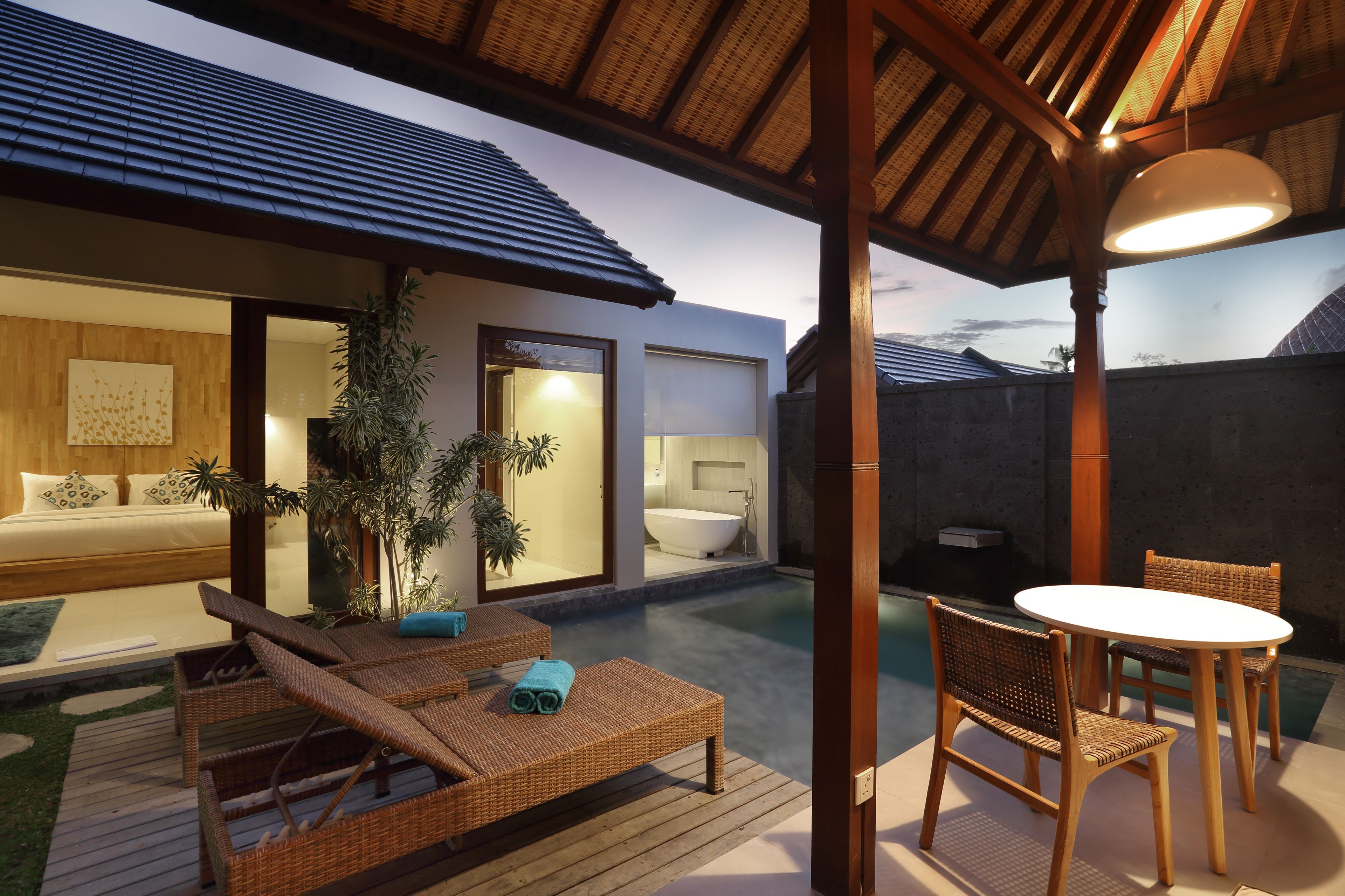 A modern outdoor living area with a pool, lounge chairs, and a dining table.