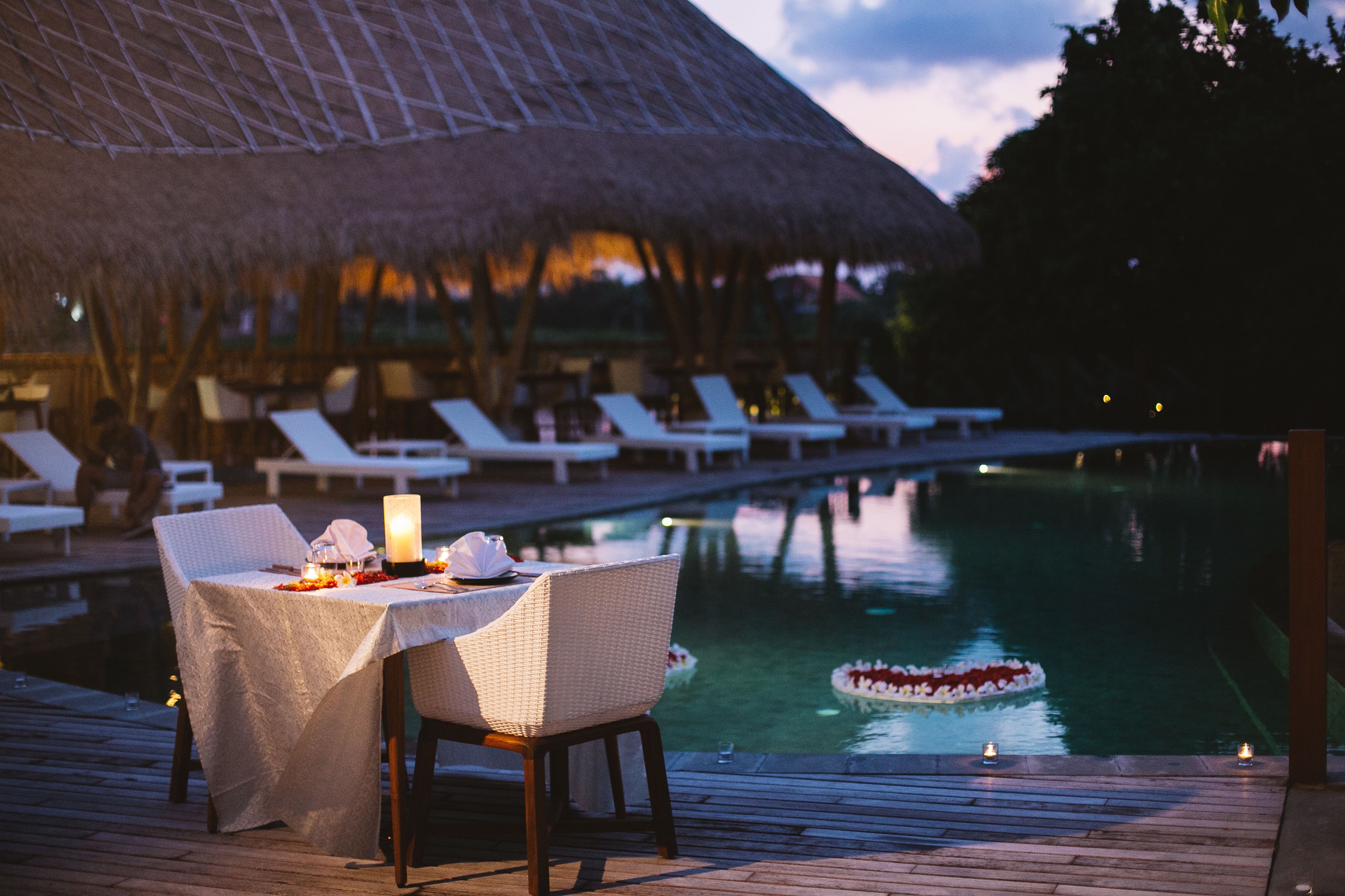 A dining area with a table set for two, overlooking a pool with a decorative float.