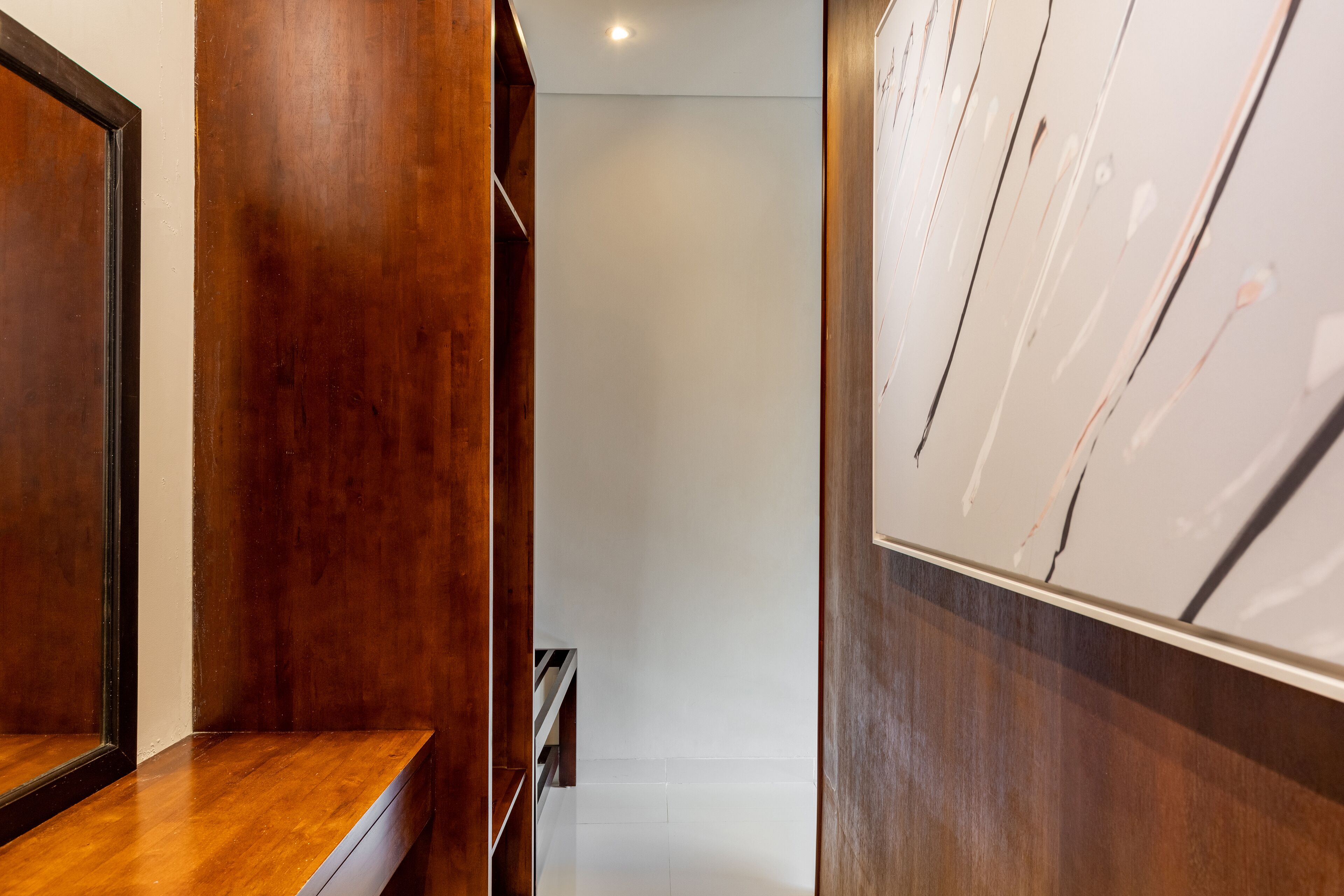 A hallway with wooden paneling, a white tiled floor, and a whiteboard on the right.