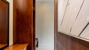 A hallway with wooden paneling, a white tiled floor, and a whiteboard on the right.