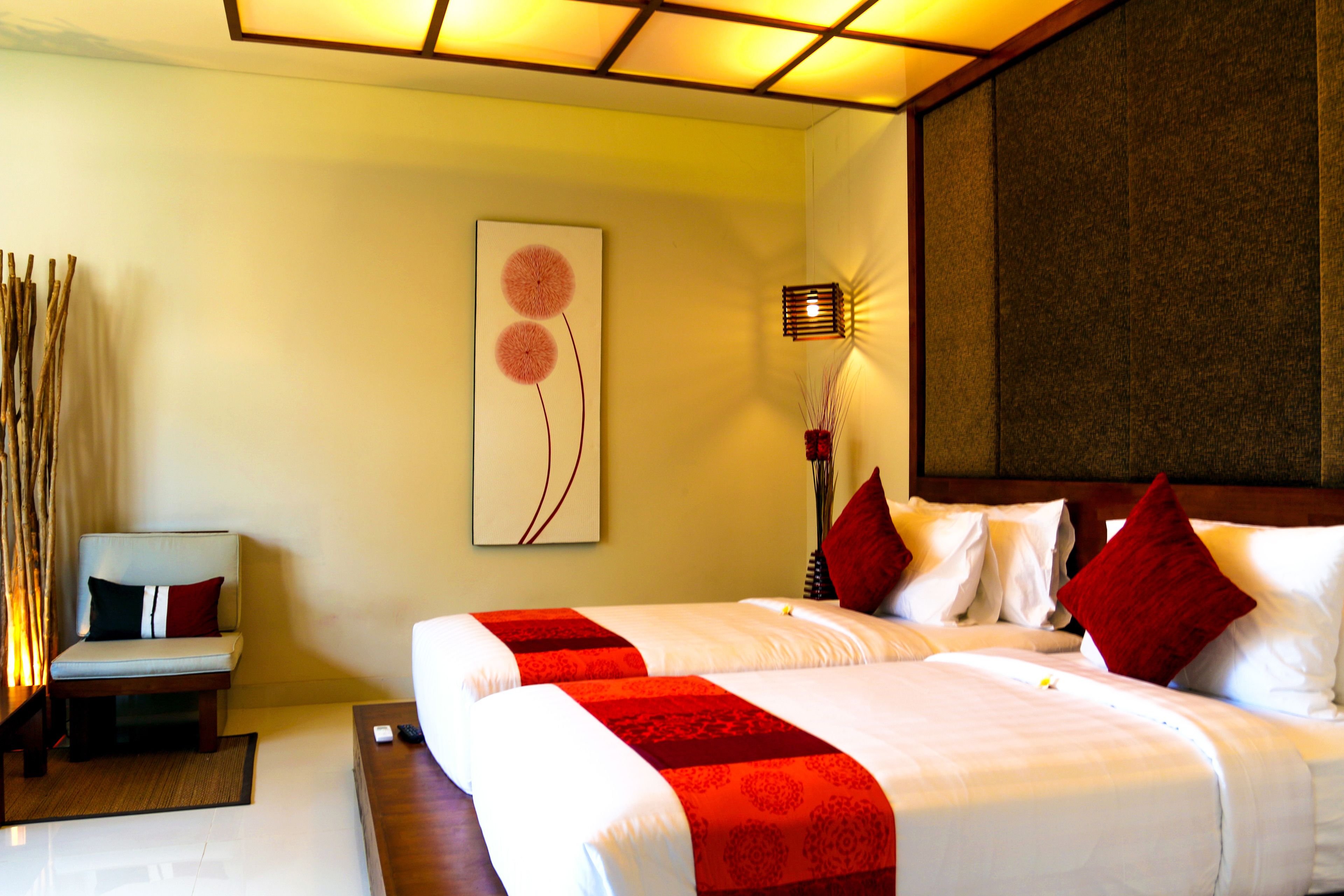 Quarto de hotel com cama grande, mesa de cabeceira, cadeira e obra de arte na parede.