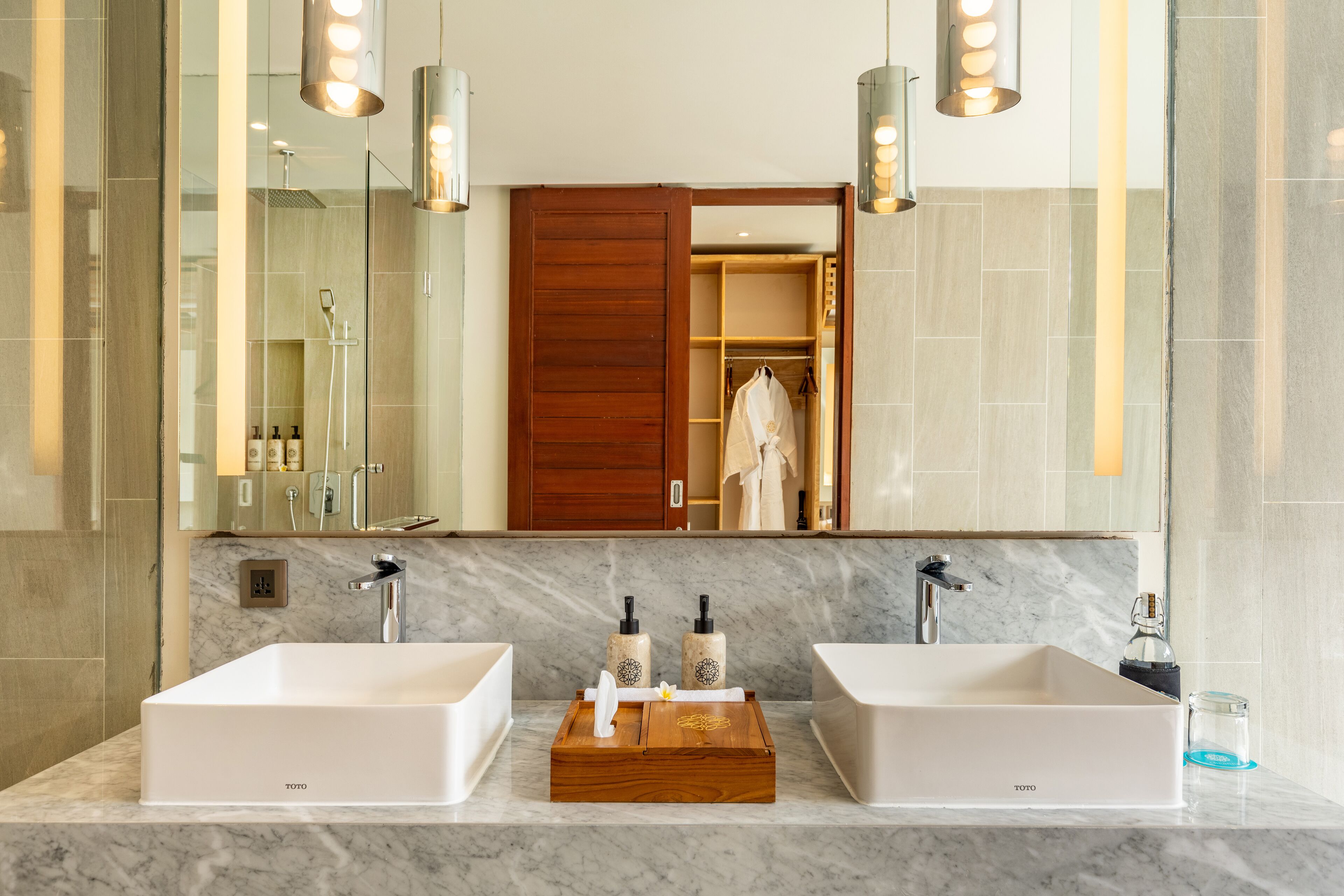A modern bathroom with two sinks, a wooden vanity, and a large mirror.