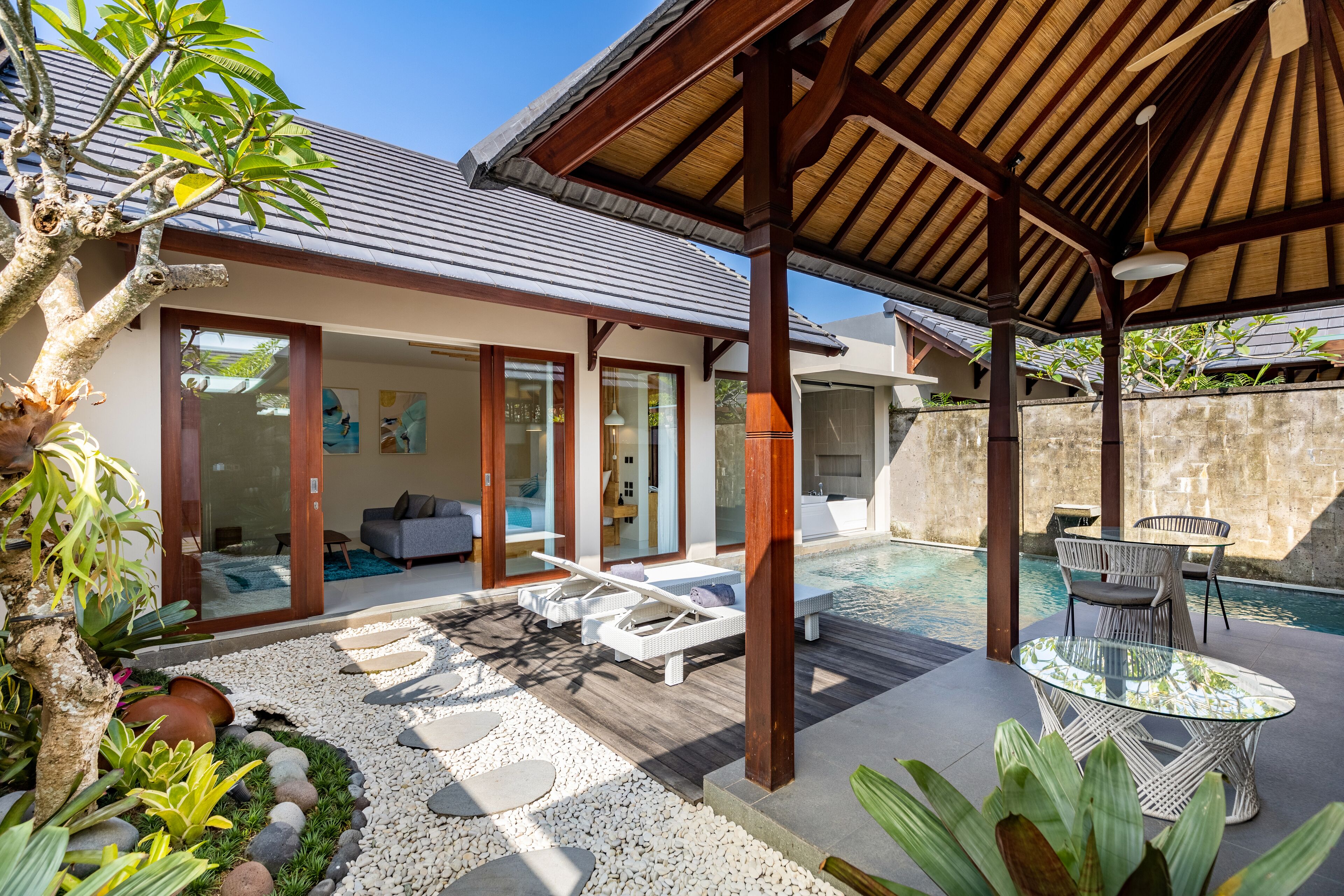 A modern house with a covered outdoor area, a pool, and a dining table.
