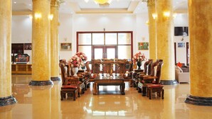 A spacious lobby with marble columns, a chandelier, and a central seating area with wooden furniture. - A1 Hotel Dien Bien (Dien Bien Phu)