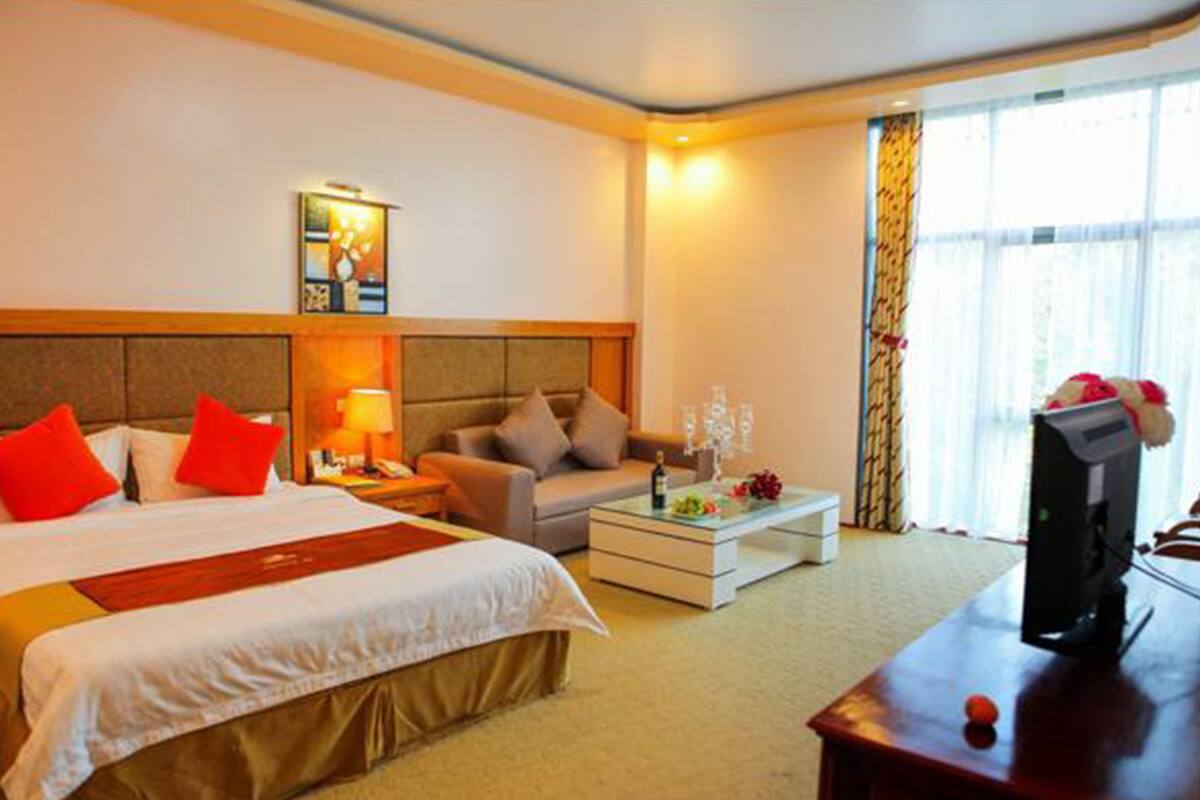 Une chambre d’hôtel avec un grand lit, un canapé, une table basse et un téléviseur.