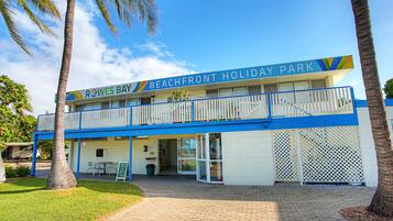 A two-story building with a sign reading "Rowes Bay Beachfront Holiday Park".