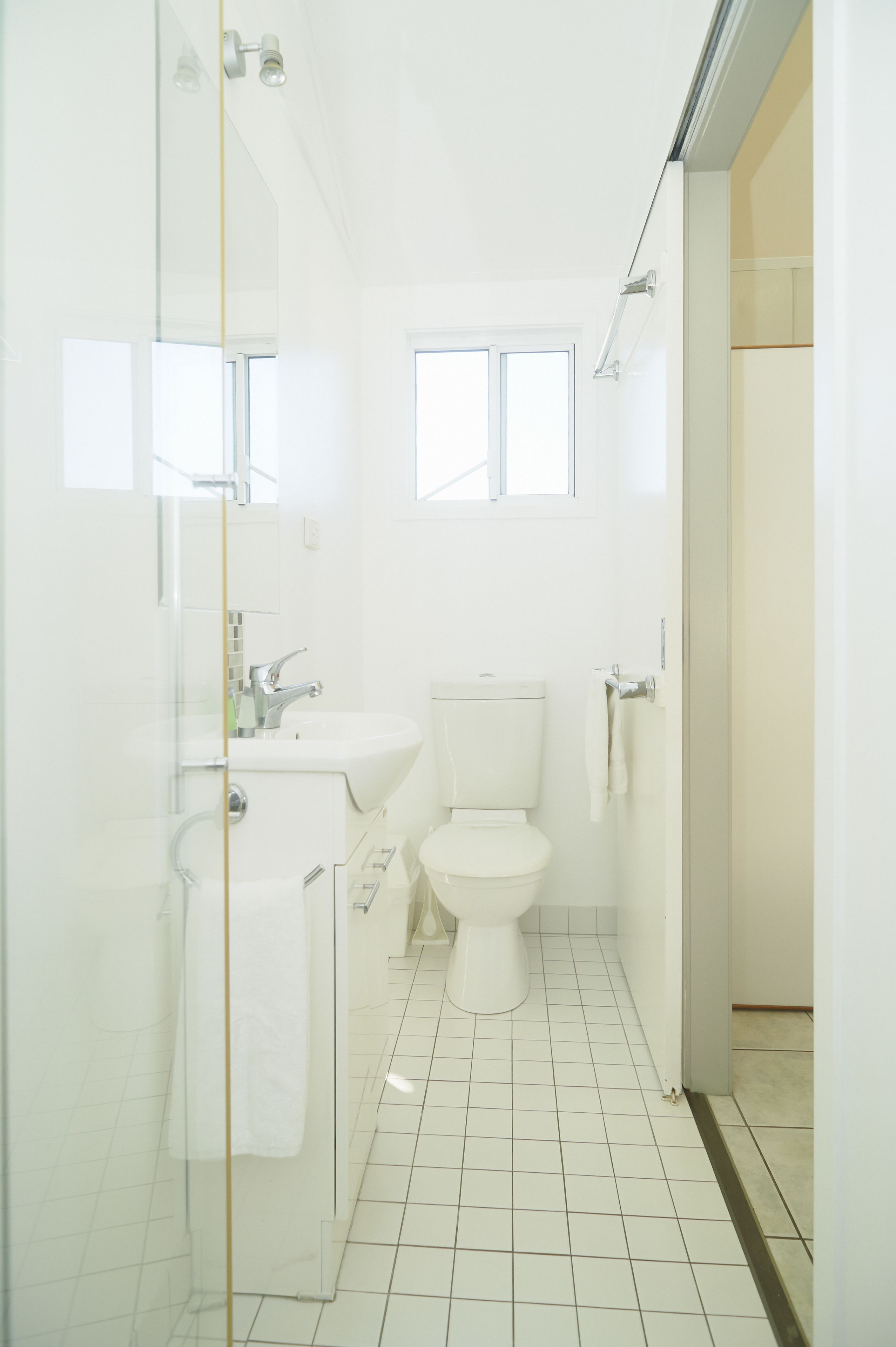 Un baño con cabina de ducha de vidrio, lavamanos blanco y retrete.