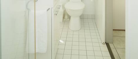 Un baño con cabina de ducha de vidrio, lavamanos blanco y retrete.