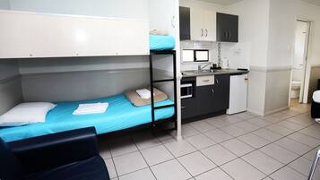 A compact room with bunk beds, a kitchenette, and a small seating area.