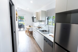 A modern kitchen with a built-in dishwasher, stainless steel appliances, and a dining area with a table and chairs.