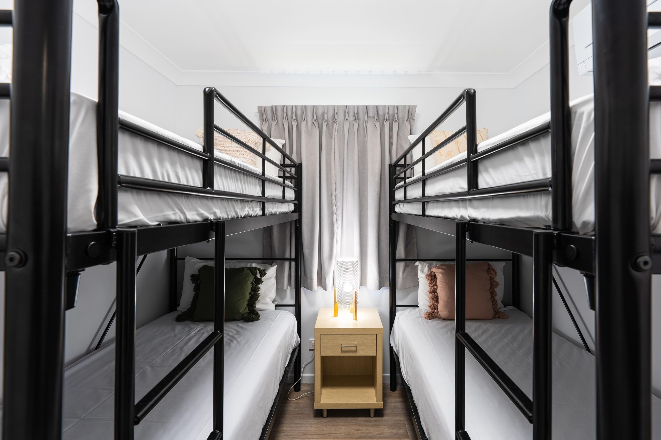 Une chambre avec deux lits superposés, une table de chevet et une fenêtre avec des rideaux.