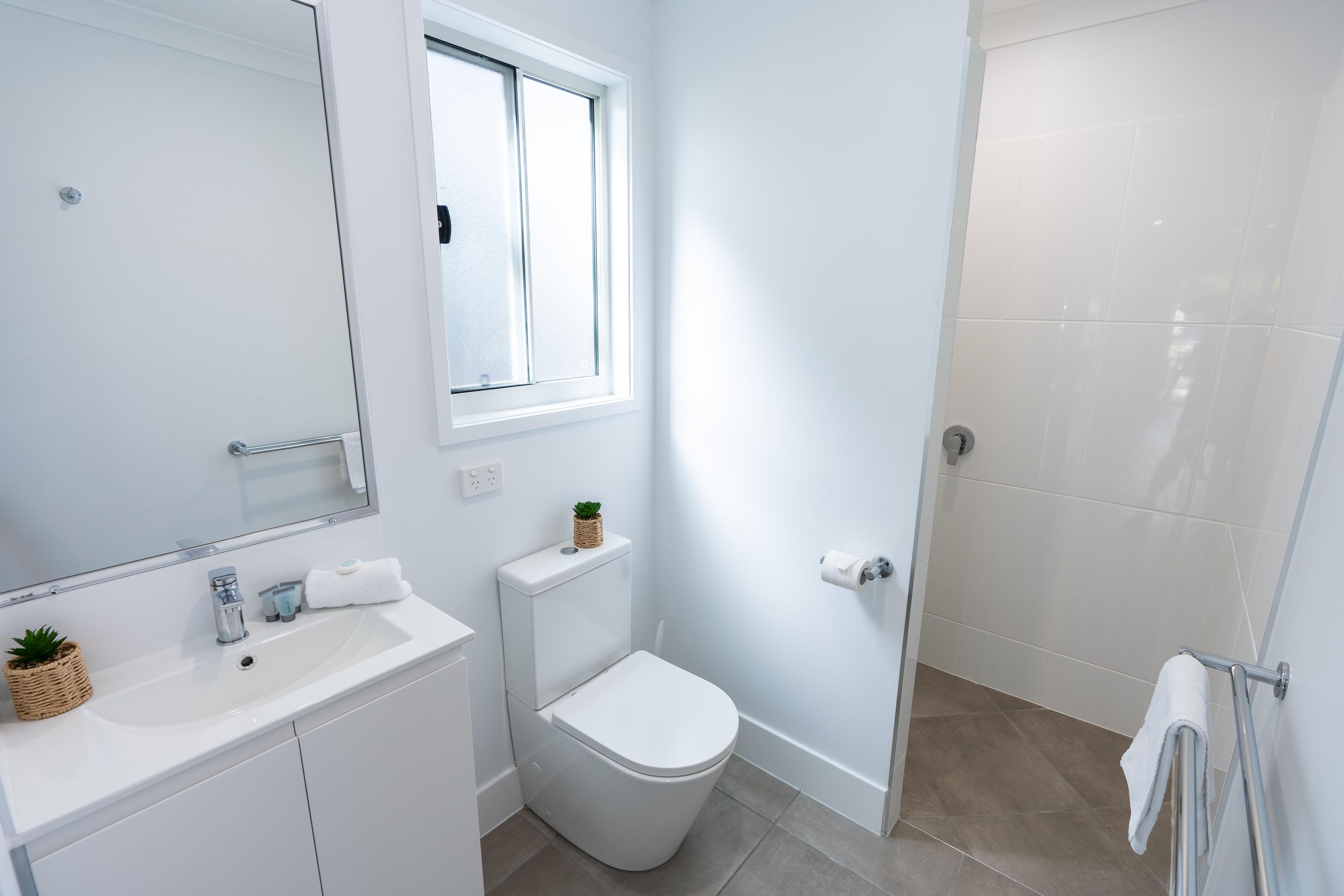 A modern bathroom with a white sink, toilet, and shower.