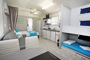 A compact hotel room with a kitchenette, a bed, and a seating area. - BIG4 Tasman Holiday Parks - Rowes Bay (Belgian Gardens)