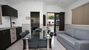 Una cocina moderna con armarios oscuros, una mesa de comedor de cristal y un sofá gris.