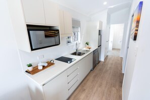 Una cuina moderna amb armaris blancs, microones integrat i vàlvula de bany de color acer inoxidable.