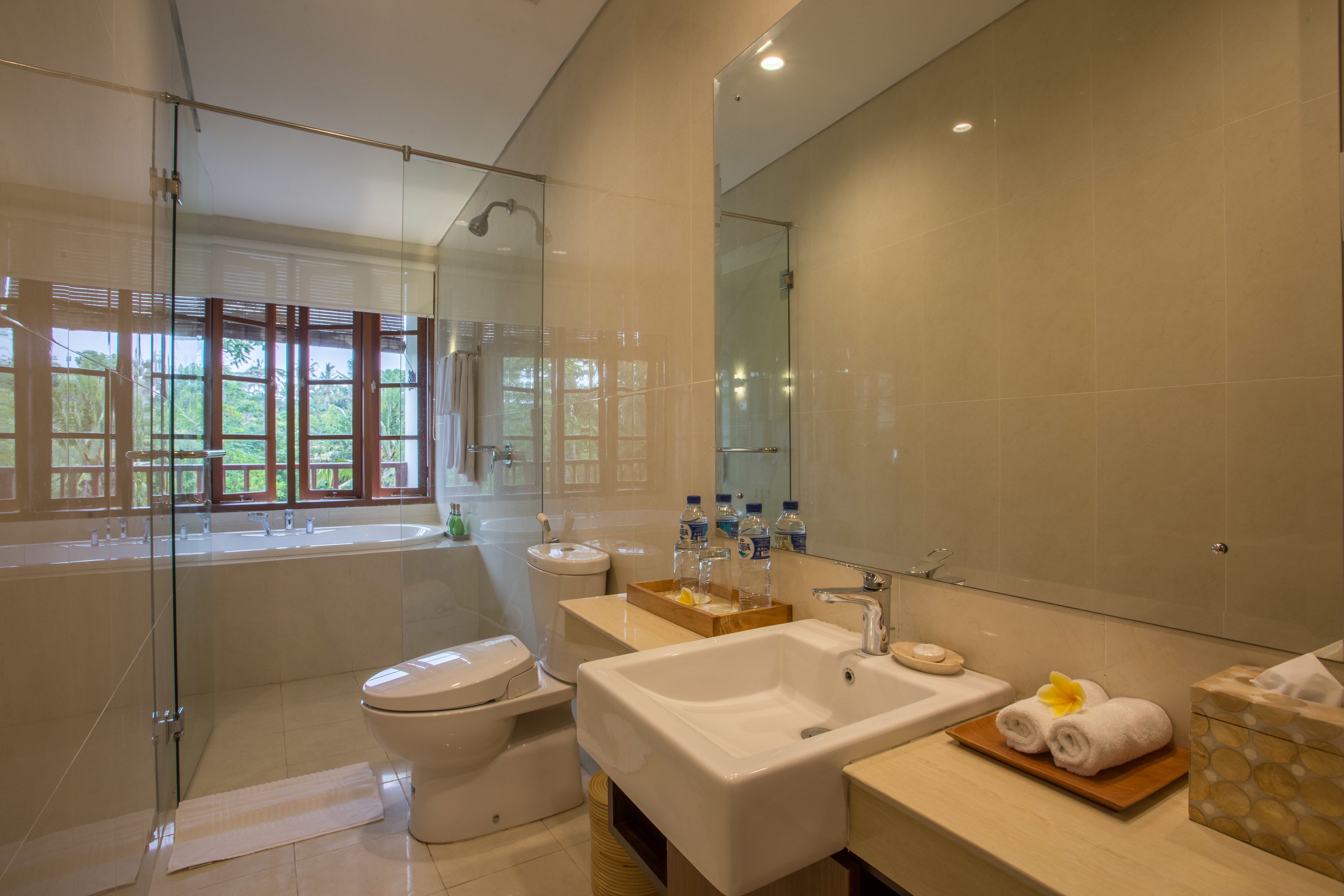 Een moderne badkamer met een glazen douchecabine, een ruime wastafel en een toilet.