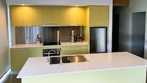 Una cocina moderna con una isla central, electrodomésticos de acero inoxidable y armarios verde claro.