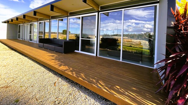 Un edificio moderno con amplios ventanales y una terraza de madera.