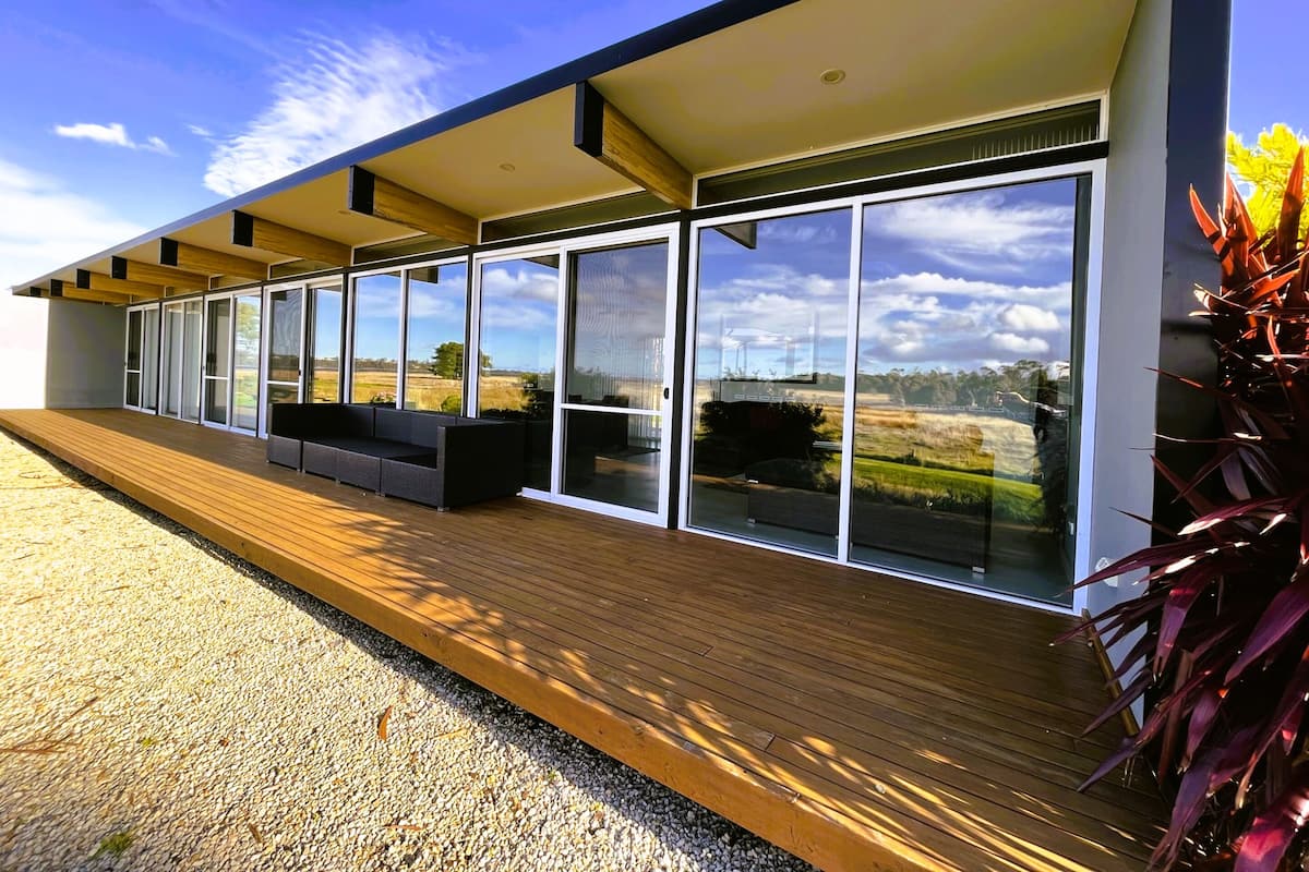Un edificio moderno con amplios ventanales y una terraza de madera.