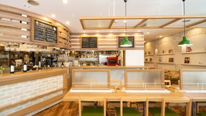 A restaurant interior with wooden furniture, a counter with a menu, and a coffee machine. - Hotel MyStays Yokohama Kannai (Yokohama)