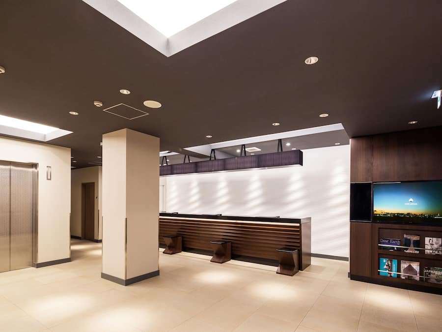 Un vestíbulo moderno con mostrador de recepción, zona de estar y una pantalla de televisión que muestra una vista panorámica.
