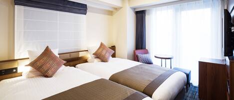 Une chambre d’hôtel avec deux lits, un bureau, une chaise et un téléviseur.