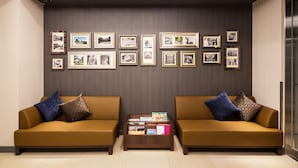 A lobby with two sofas, a coffee table, and a wall with framed pictures. - Hotel MyStays Yokohama Kannai (Yokohama)