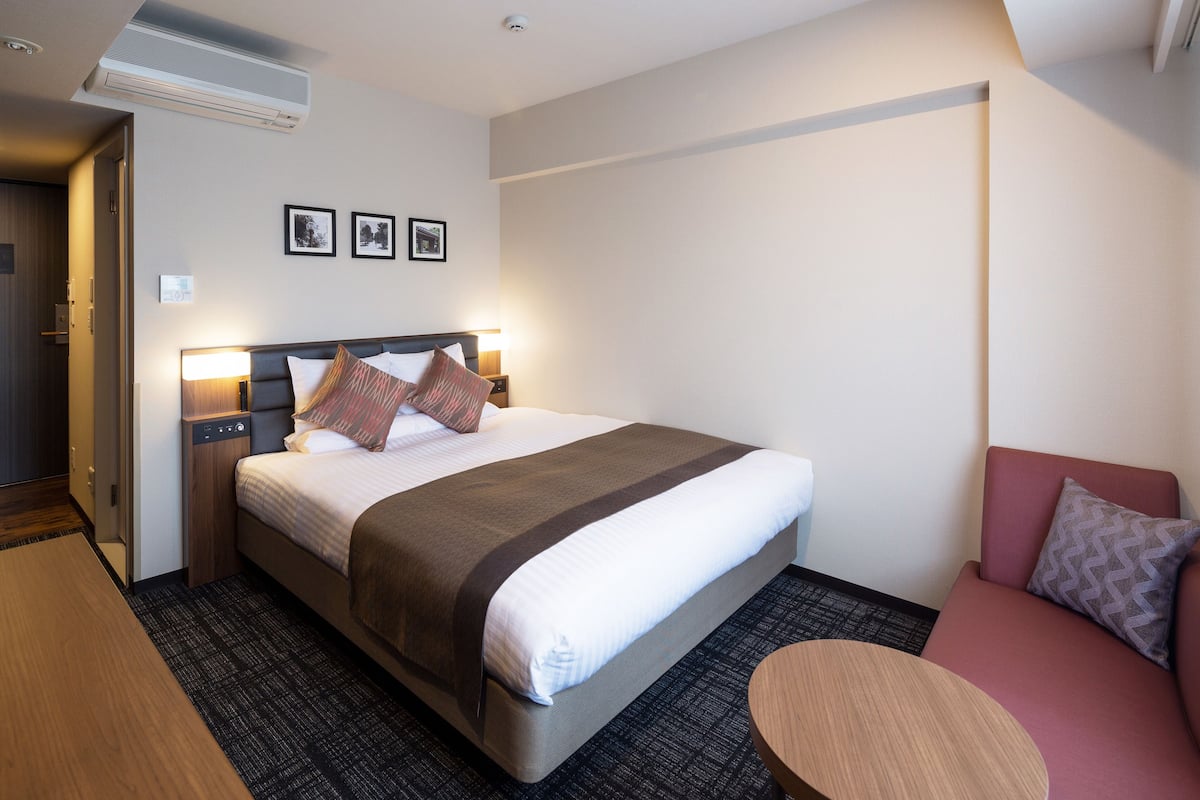 Ein Hotelzimmer mit einem Bett, Nachttischen, einem kleinen runden Tisch und einer Couch.