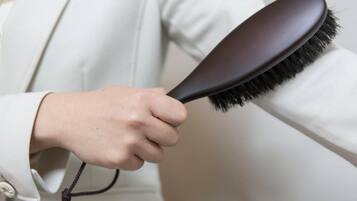 A person holding a hairbrush with a dark handle and black bristles.
