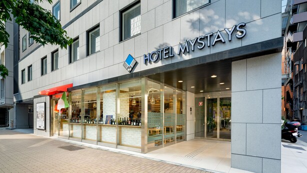 A modern hotel facade with a clear entrance, large windows, and a visible bar area. - Hotel MyStays Yokohama Kannai (Yokohama)