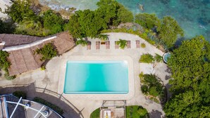 An aerial view of a resort with a swimming pool surrounded by palm trees and a beach. - Granada Beach Resort - Adults Only (Boljoon)