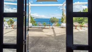 An open door revealing a balcony with outdoor seating, a view of the sea, and a fire exit sign. - Granada Beach Resort - Adults Only (Boljoon)