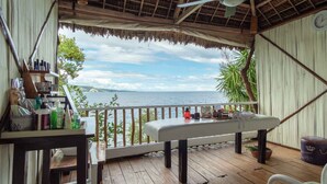 A wooden deck with a table and chairs, overlooking a body of water. - Granada Beach Resort - Adults Only (Boljoon)